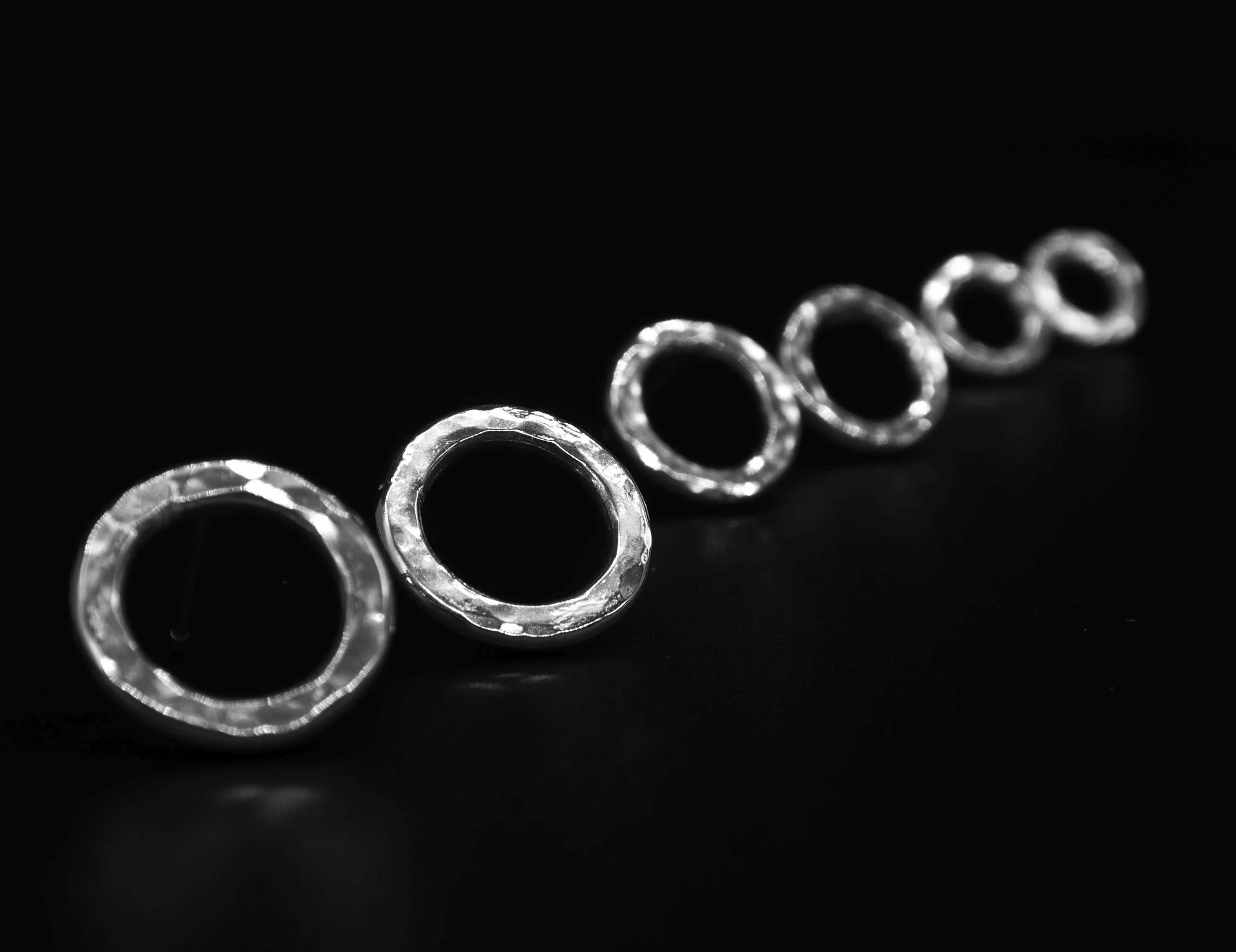 Angled view of a row of the sterling silver Vanilla earrings showing the handmade textured finish. 