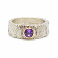 textured handmade silver ring with a purple sapphire set in gold