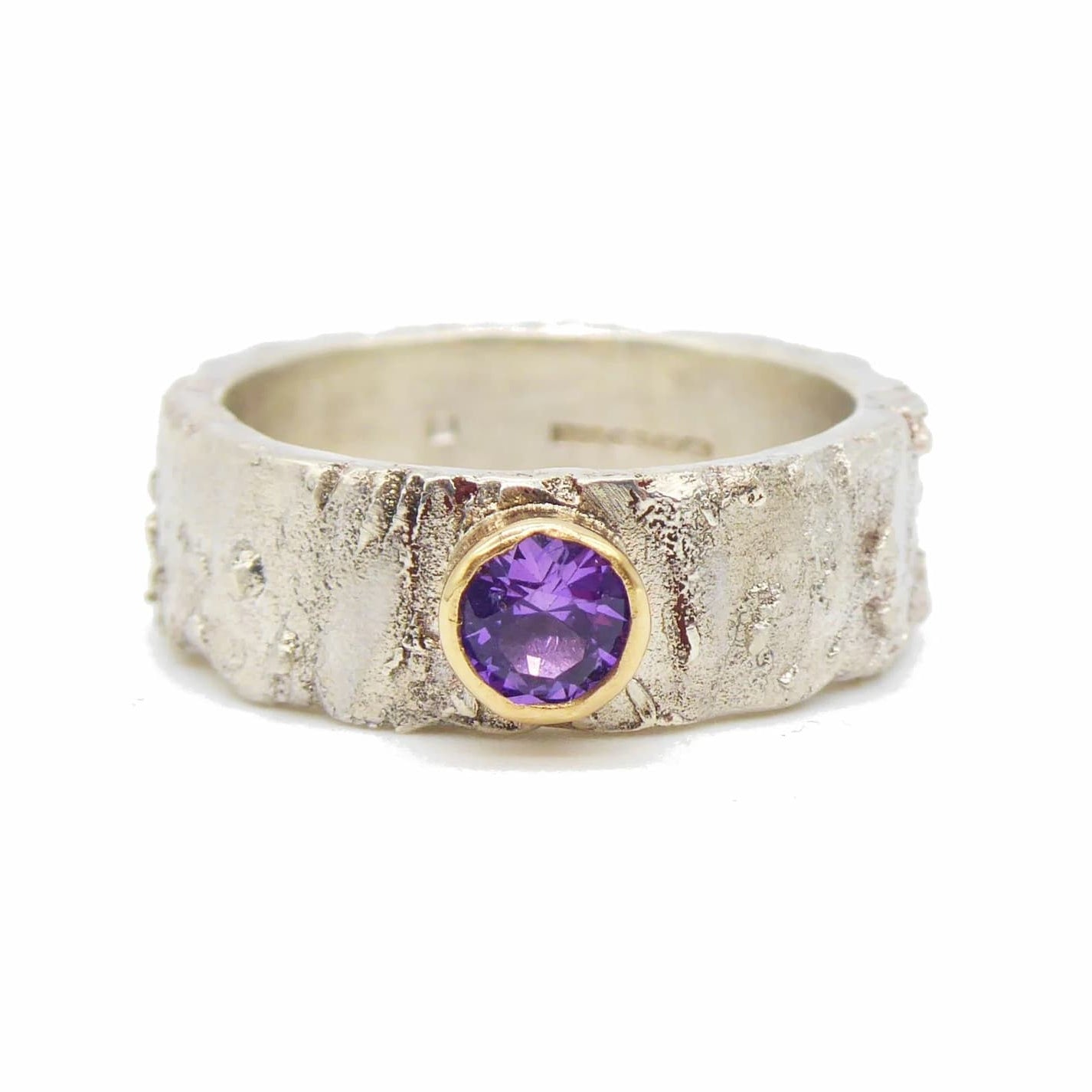 textured handmade silver ring with a purple sapphire set in gold