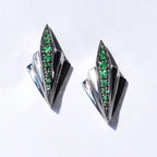 Front view of the Art Deco sterling silver earrings featuring green tsavorite garnets and a black geometric design.