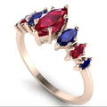 Angled view of the Harlequin ruby and blue sapphire ring in 18ct rose gold, showing graduating marquise-cut gemstones in claw settings.