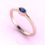 Angled view of an 18ct rose gold ring with a horizontal marquise sapphire and delicate milgrain textured edges.