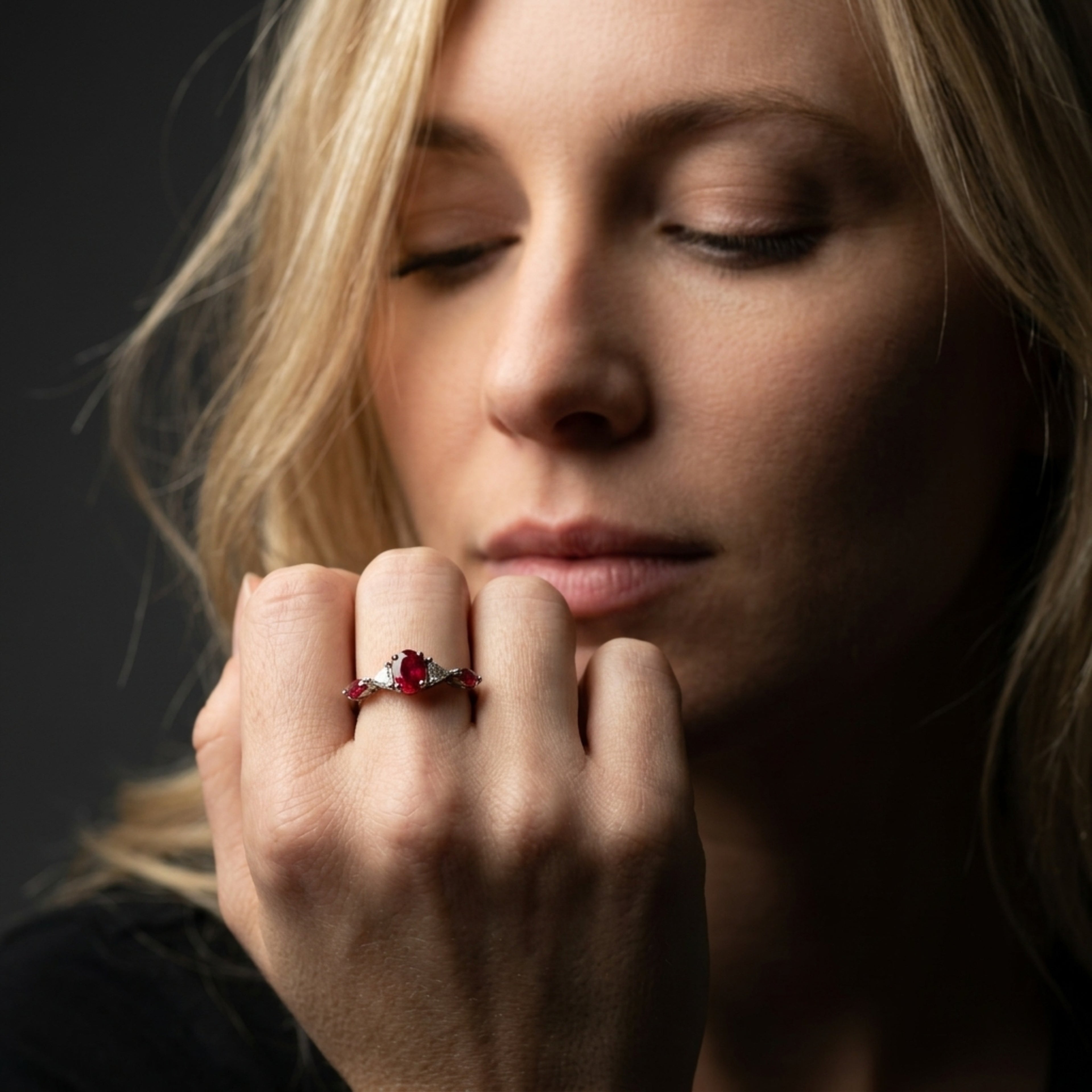 Maisie oval ruby and diamond engagement ring worn on hand, showing vivid oval ruby centre stone with trillion diamond and marquise ruby accents in white gold