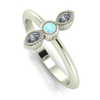 Angled perspective of the aquamarine and diamond trilogy ring, showing the delicate beaded metalwork and the light blue tones of the gemstones.