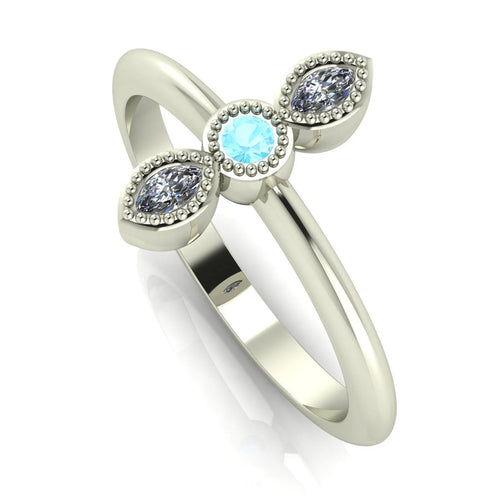 Angled perspective of the aquamarine and diamond trilogy ring, showing the delicate beaded metalwork and the light blue tones of the gemstones.