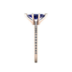 Close-up side view of the 18ct rose gold Amoret ring highlighting the secure claw setting for the blue sapphire and the grain-set shoulder diamonds.