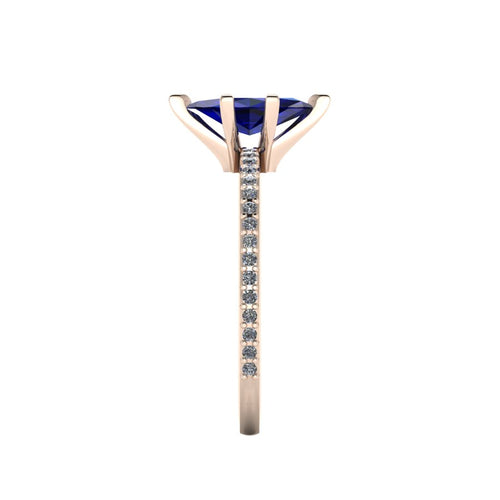 Close-up side view of the 18ct rose gold Amoret ring highlighting the secure claw setting for the blue sapphire and the grain-set shoulder diamonds.
