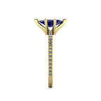 Close-up side view of the 18ct yellow gold Amoret ring highlighting the secure claw setting for the blue sapphire and the grain-set shoulder diamonds.