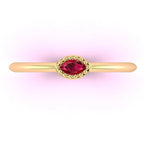 Top down view of a Mini Astraea ring featuring a horizontal marquise ruby set in a beaded 18ct yellow gold band.