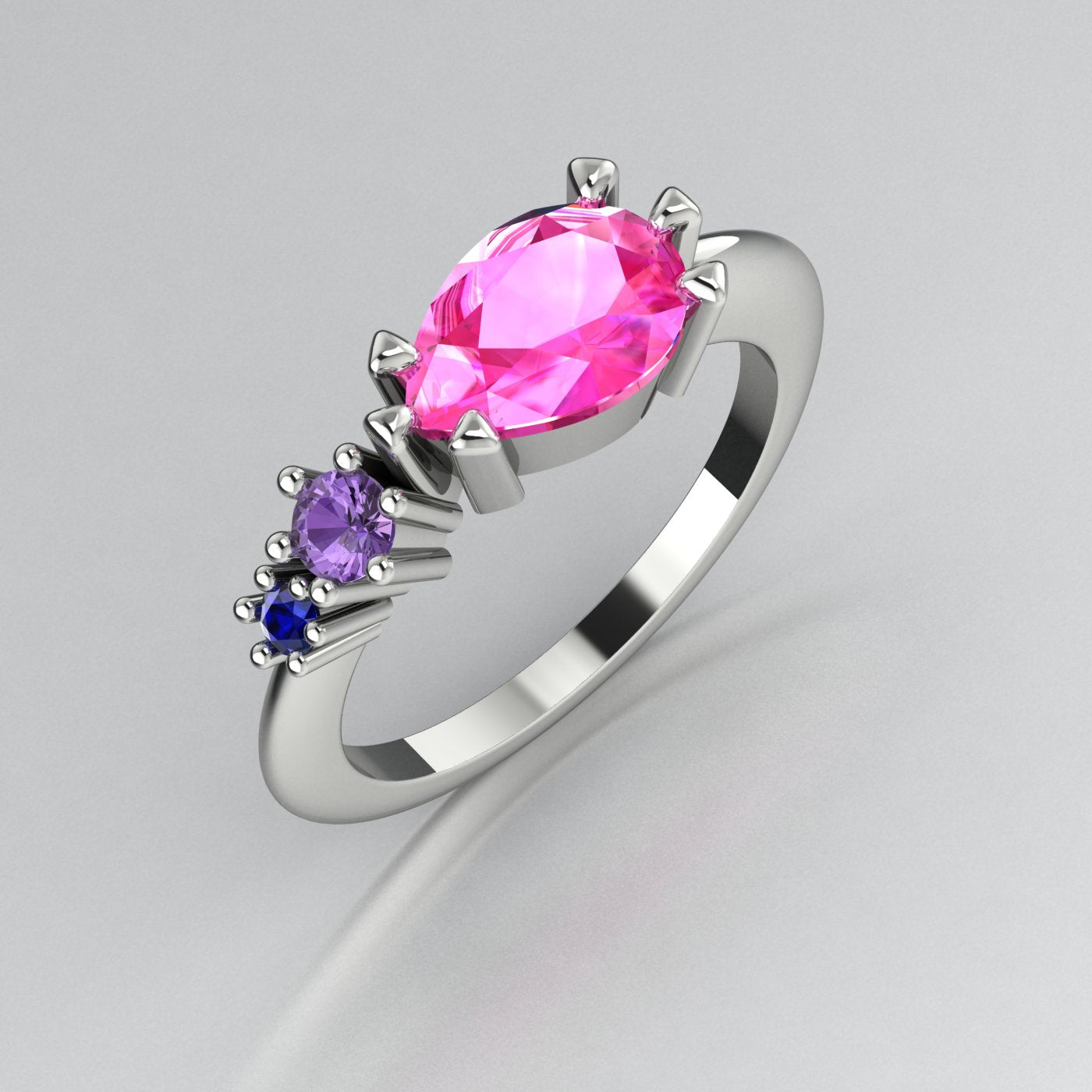 Pear shaped pink sapphire, violet sapphire and blue sapphire asymmetrical Comet engagement ring in 18ct white gold, angled three-quarter view showing all three stones
