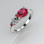 Pear shaped ruby, diamond and ruby accent asymmetrical Comet engagement ring in 18ct white gold, angled view showing diamond and ruby accents