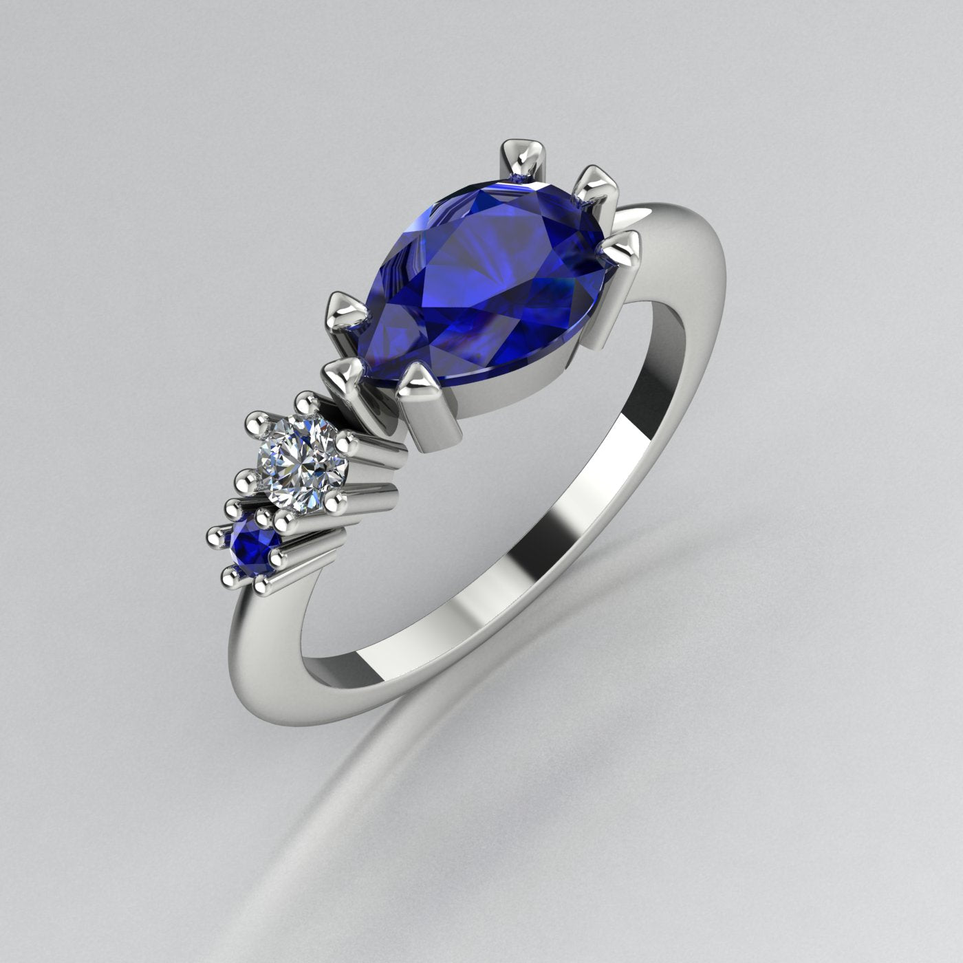 Pear shaped blue sapphire and diamond asymmetrical Comet engagement ring in 18ct white gold, angled view