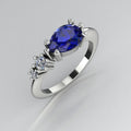 Pear shaped blue sapphire and two diamond asymmetrical Comet engagement ring in 18ct white gold, angled view showing two diamond accents