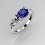 Pear shaped blue sapphire and two diamond asymmetrical Comet engagement ring in 18ct white gold, angled view showing two diamond accents