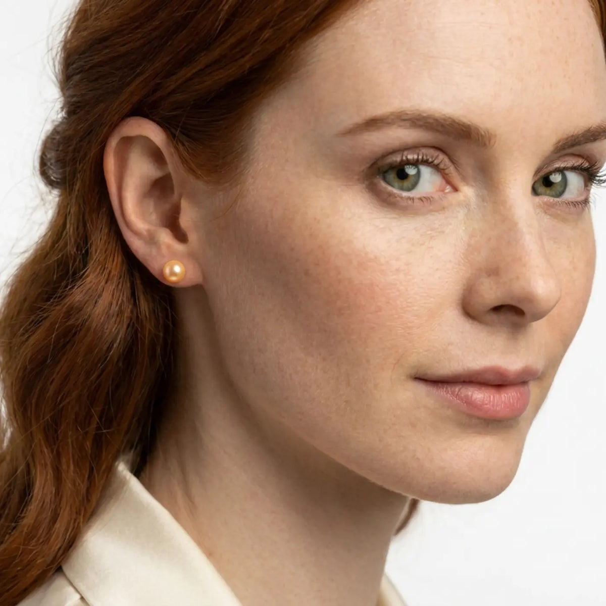 Model wearing peach freshwater pearl stud earrings with sterling silver fittings by Nude Jewellery.