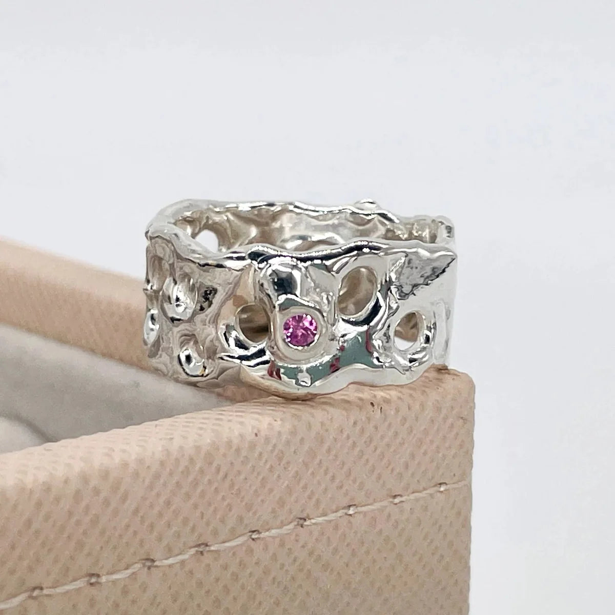 Origin Honeycomb Ring in recycled sterling silver with a brilliant-cut pink sapphire, shown on a beige jewellery box