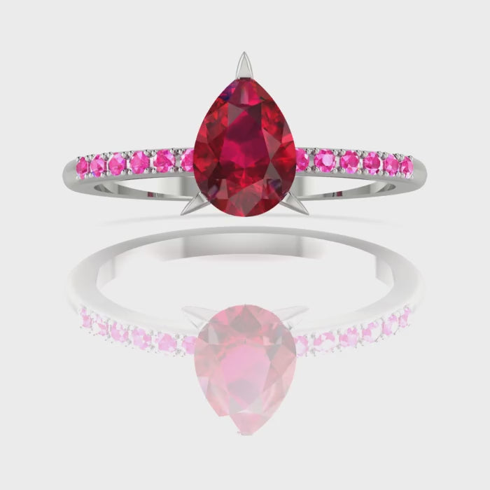 Video of the Calista ruby ring, capturing the rich, fiery shimmer of the red pear centre stone and the bright pink sapphire shoulders against polished white gold or platinum.
