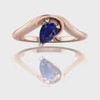 Enchanted pear shaped blue sapphire asymmetric solitaire engagement ring in rose gold, rotating 360 view showing sculptural band and deep blue sapphire