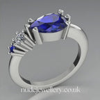 Pear shaped blue sapphire and diamond asymmetrical Comet engagement ring in 18ct white gold, 360 degree view