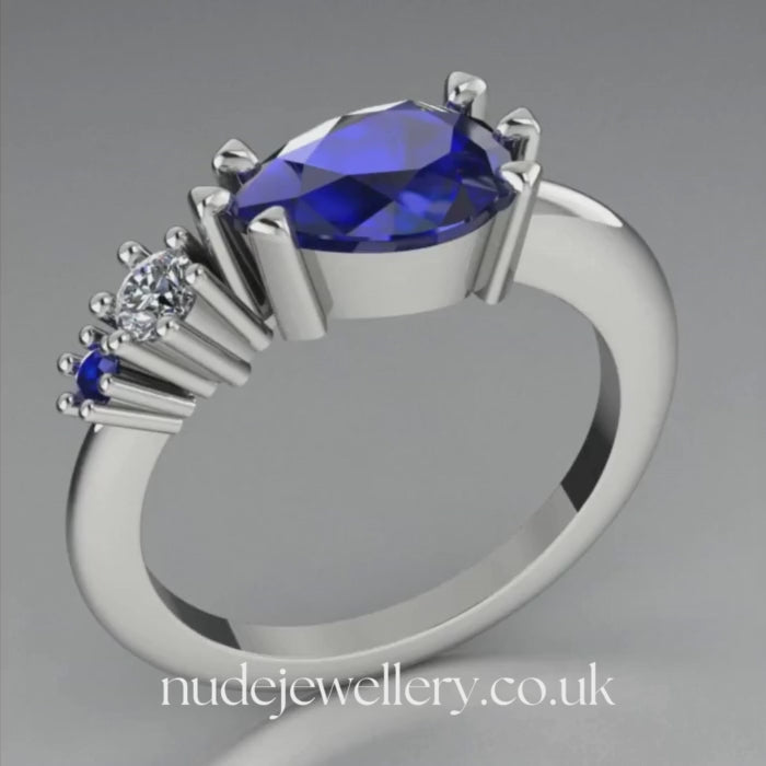 Pear shaped blue sapphire and diamond asymmetrical Comet engagement ring in 18ct white gold, 360 degree view