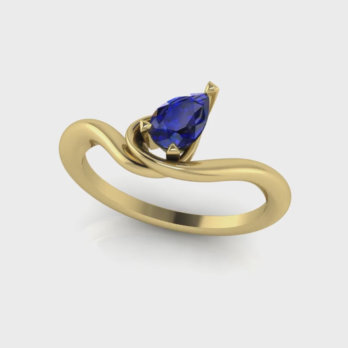 Enchanted pear shaped blue sapphire asymmetric solitaire engagement ring in yellow gold, rotating 360 view showing sculptural band and deep blue sapphire