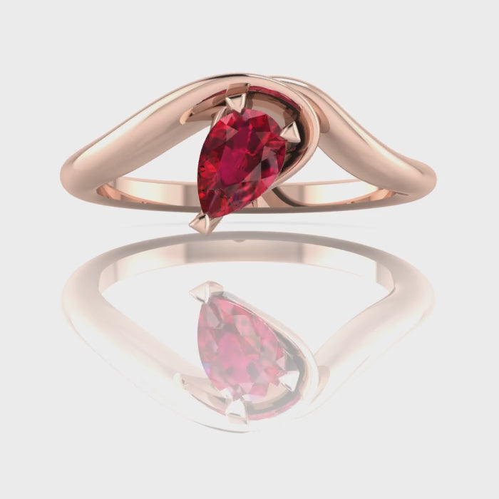 Enchanted pear shaped ruby asymmetric solitaire engagement ring in rose gold, rotating 360 view showing sculptural band and deep red ruby