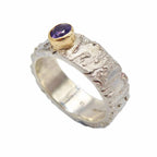 textured handmade silver ring with a purple sapphire set in gold - angled view