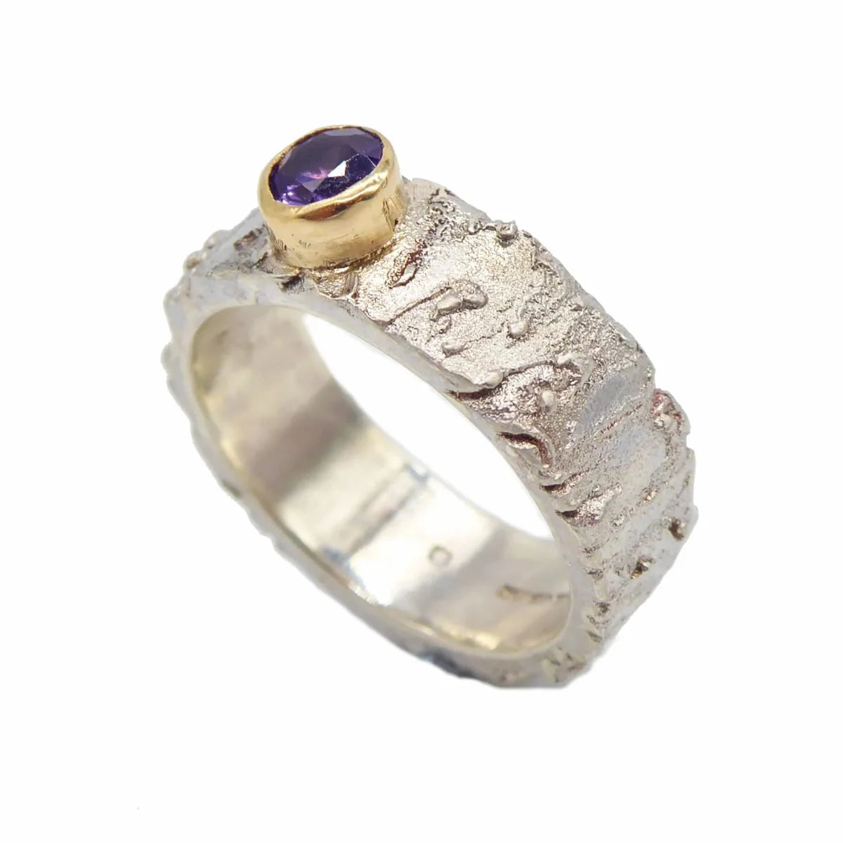 Angled view of the Rivda purple sapphire ring showing its organic textured sterling silver band and 9ct yellow gold setting