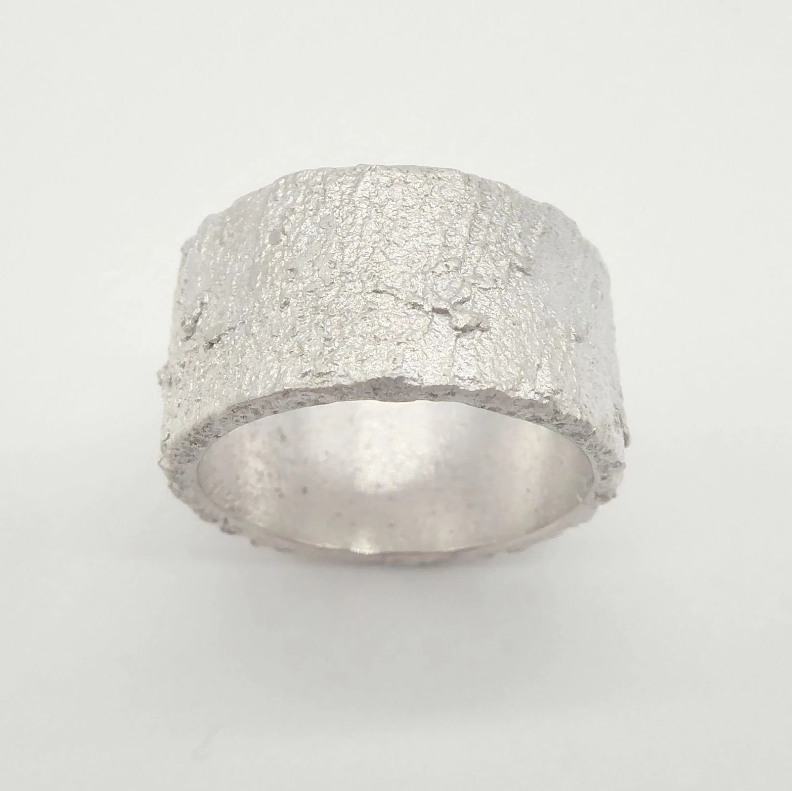 Top view of the Rivda Frozen Sand 10mm silver band showing the organic hand-forged texture and substantial width
