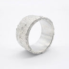 Profile view of the Rivda Frozen Sand 10mm silver band showing the organic hand-forged texture and substantial width