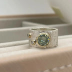 Close-up of the Rivda moissanite and diamond ring with a central moissanite and two diamond accents, displayed on a tray