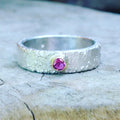 Silver textured ring with a ruby gemstone set in a gold setting.