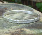 Rivda Frozen Sand handmade silver bangle on bark surface showing organic texture detail