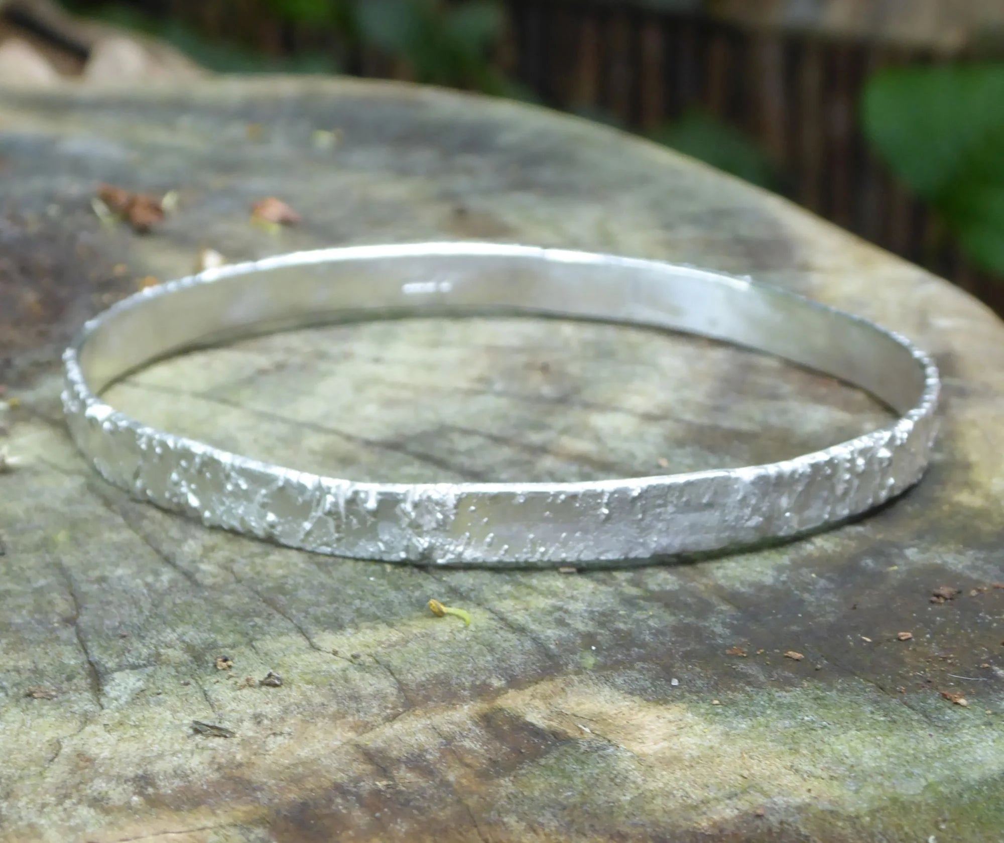 Rivda Frozen Sand handmade silver bangle on bark surface showing organic texture detail