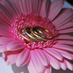 Handmade 18ct rose gold eternity ring set with brilliant cut diamonds sitting in a group on a pink flower.