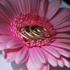 Handmade 18ct rose gold eternity ring set with brilliant cut diamonds sitting in a group on a pink flower.