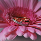 Handmade 18ct rose gold wave-shaped eternity ring featuring a curved band set with pave diamonds sitting on a flower.