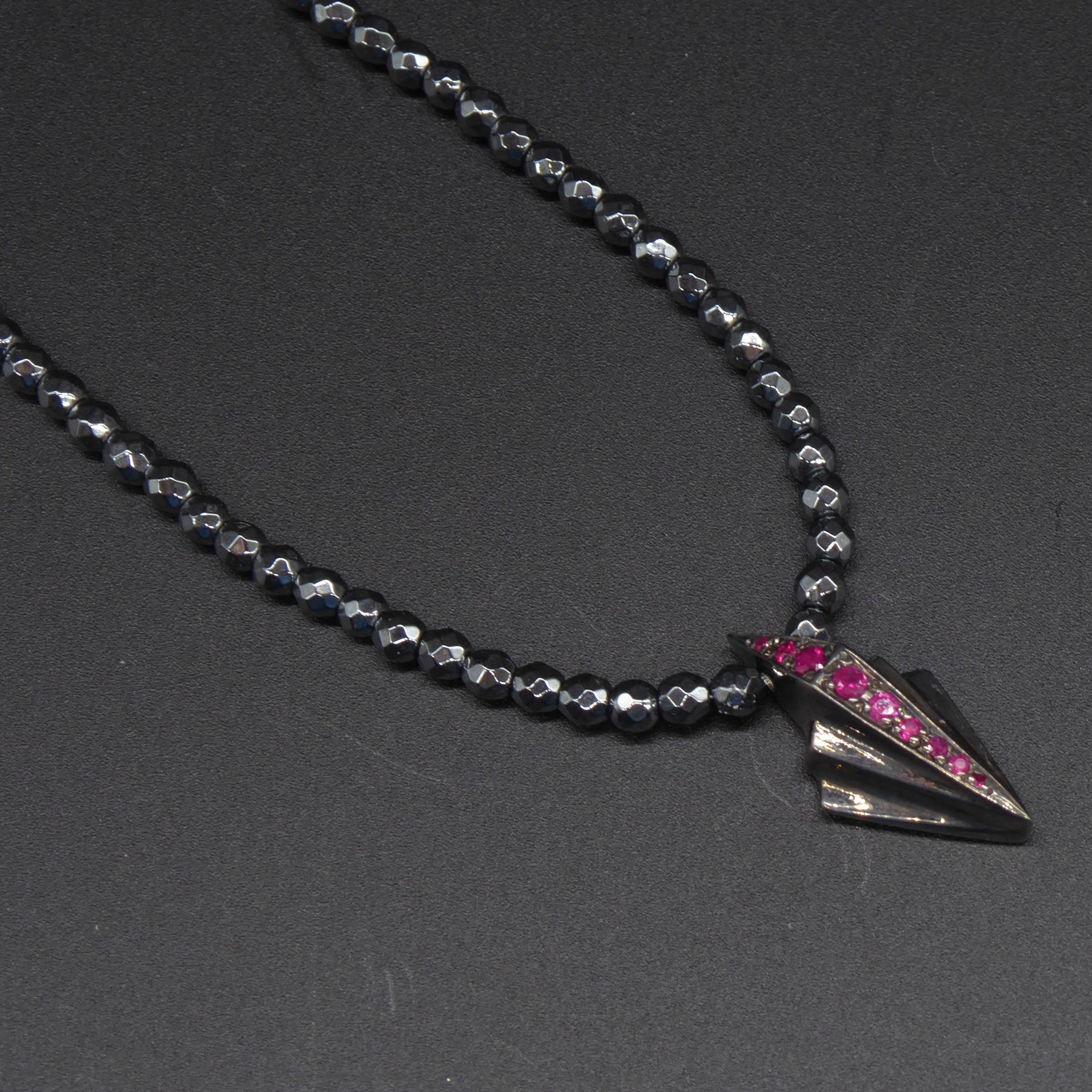 Front view of the silver Art Deco necklace featuring pave set rubies and faceted hematite gemstone beads.