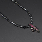 Close-up of Art Deco silver pendant set with rubies on faceted hematite bead necklace, angled view