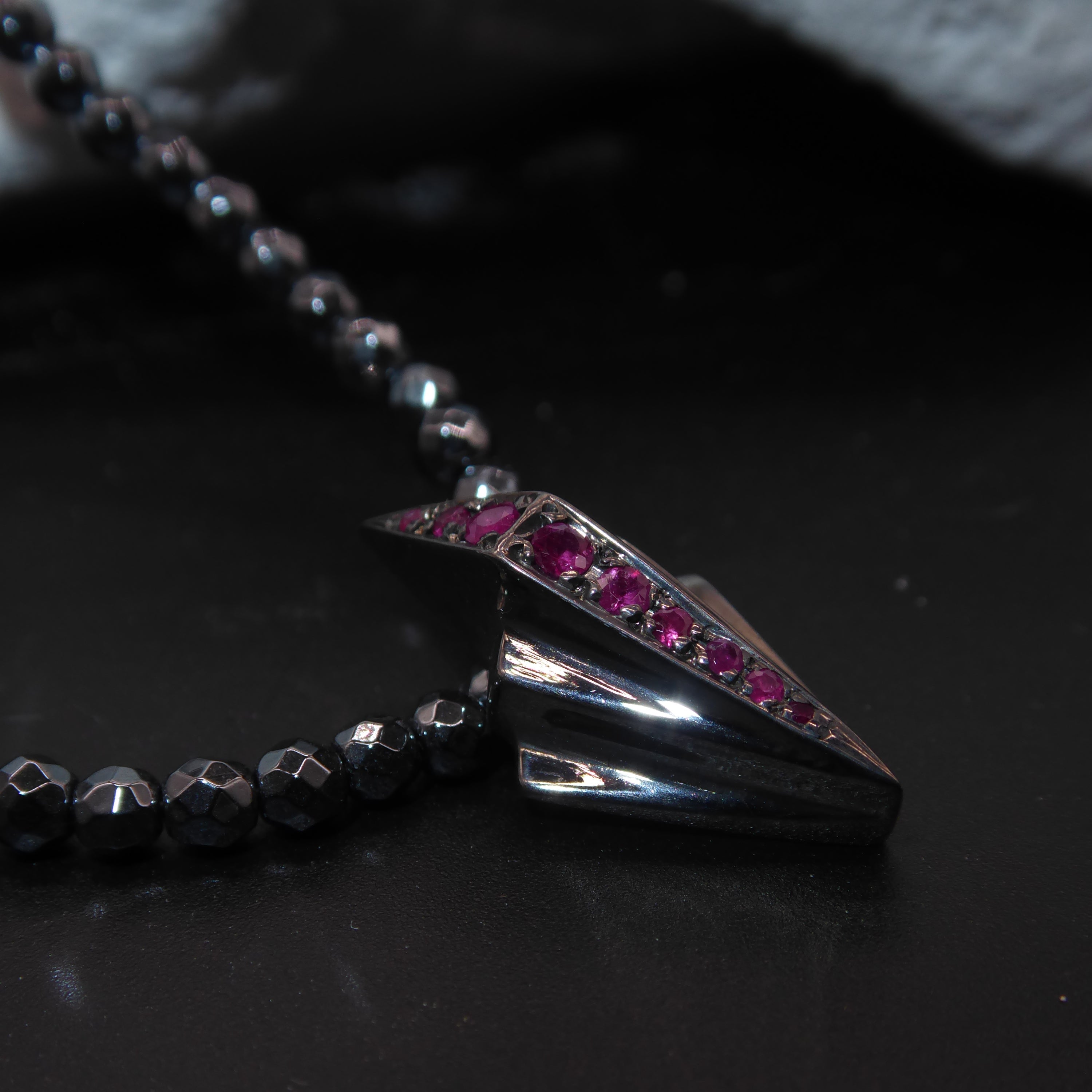 Close-up detail of the vibrant red rubies set within the geometric silver Art Deco pendant.