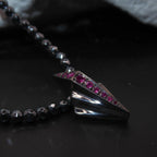Close-up of Art Deco silver pendant set with rubies on faceted hematite bead necklace, angled view