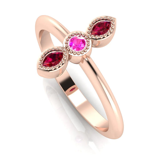 Angled perspective of an 18ct rose gold trilogy ring with a ruby and pink sapphires featuring fine milgrain textured edges.
