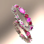 A three-quarter studio view of the Fire eternity ring in white gold, showing the alternating marquise-cut pink sapphires and brilliant-cut rubies in their claw settings.