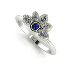 Angled view of a sapphire and marquise diamond cluster ring in a white gold or platinum setting with beaded details.