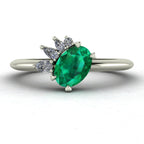 Selene cluster engagement ring, featuring a vibrant oval emerald nestled within an asymmetric white diamond arrangement on a white metal band.