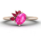 Selene cluster engagement ring, featuring a vibrant oval pink sapphire nestled within an asymmetric crown of rich red rubies on a rose gold band.