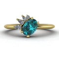 Selene oval teal sapphire and diamond engagement ring in 18ct yellow gold front view showing asymmetric pear and round diamond cluster