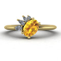 Selene cluster engagement ring, showcasing a bright oval yellow sapphire nestled within an asymmetric arrangement of white diamonds on a yellow gold band.