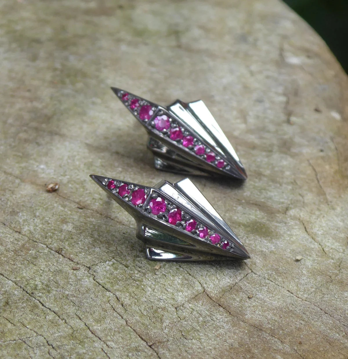 Art Deco silver ruby stud earrings with geometric fan design, shown as a pair on natural wood surface