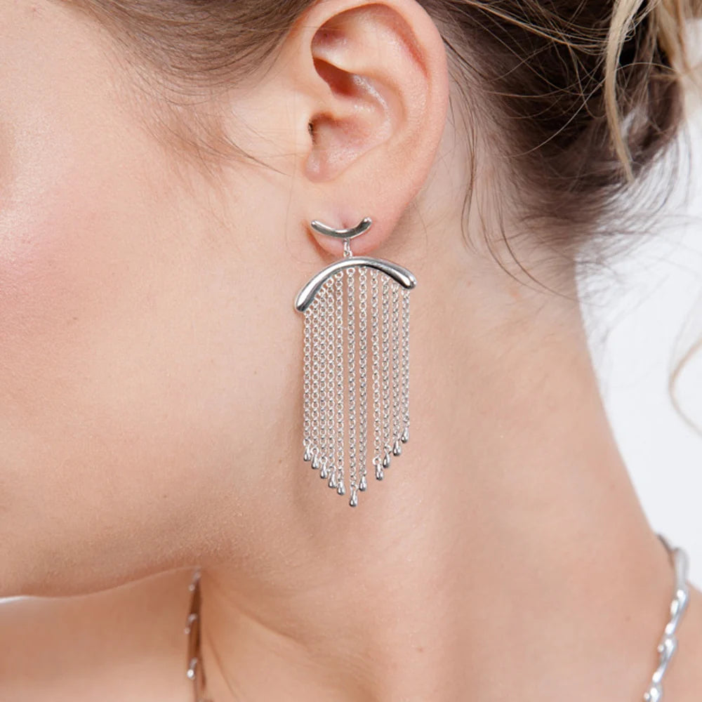 Silver Falling Earring worn on a model’s left ear, showing cascading droplet-tipped chains suspended beneath a polished silver arch.